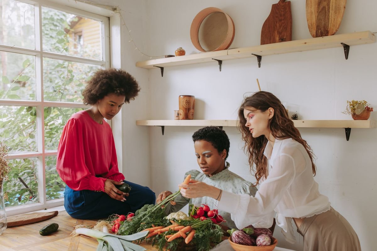 A small group preparing fresh vegetables together in a bright kitchen