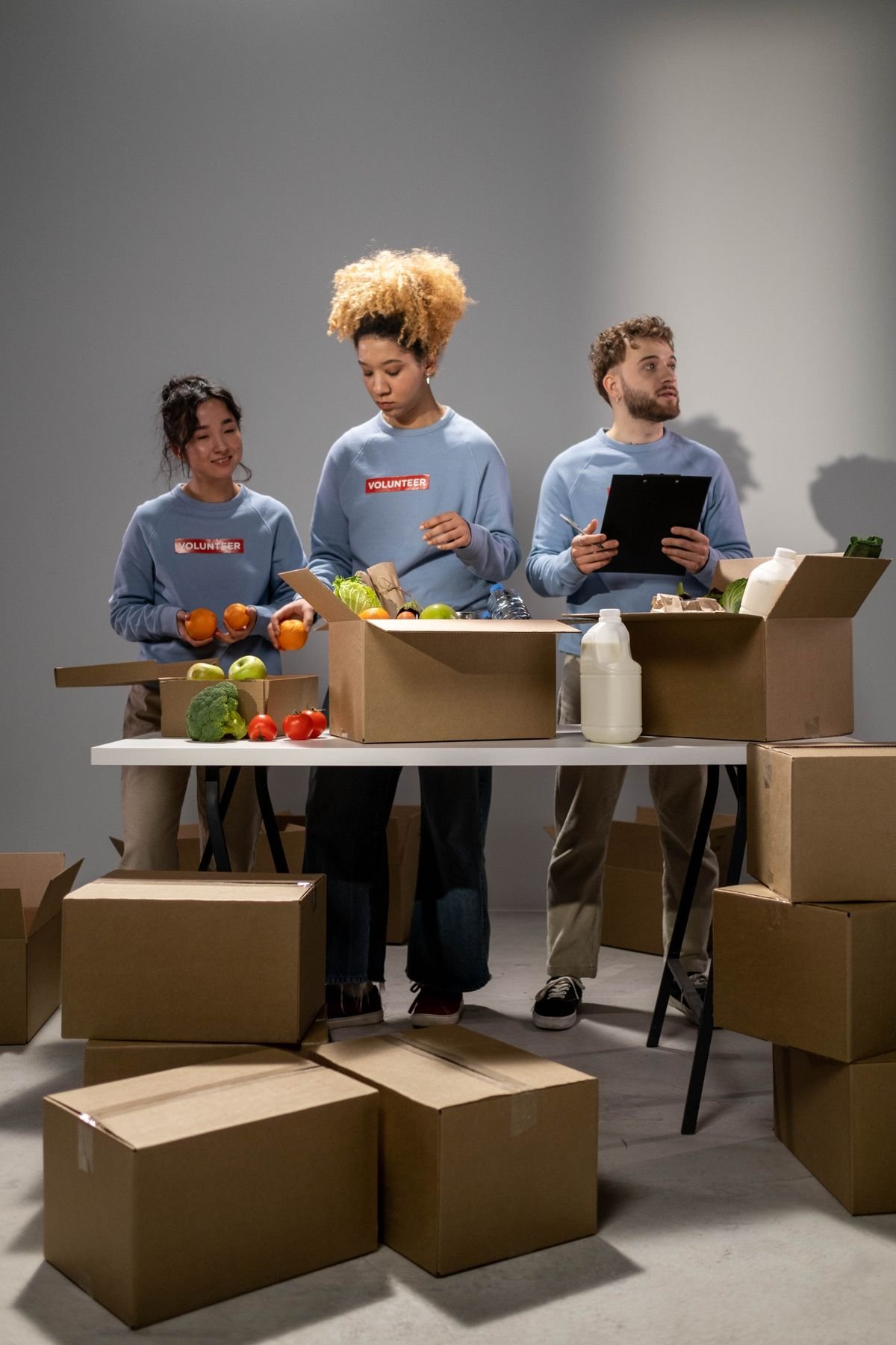 Three volunteers packing boxes of food donations together